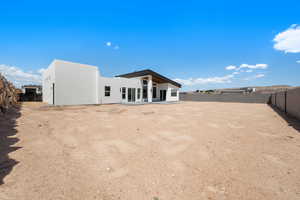Back of property featuring a fenced backyard, stucco siding, and a patio