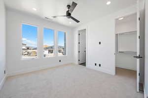 Unfurnished bedroom with carpet, a spacious closet, recessed lighting, baseboards, and a ceiling fan