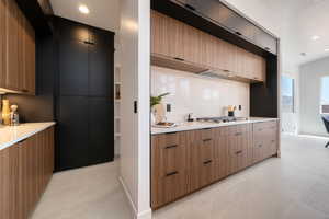Kitchen featuring modern cabinets, light countertops, stainless steel gas cooktop, light tile patterned floors, and decorative backsplash