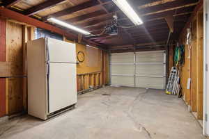 Garage featuring freestanding refrigerator and a garage door opener
