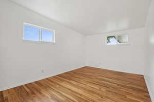 Empty room with light wood-type flooring, baseboards, and vaulted ceiling