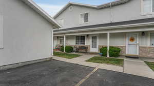 Entrance to property with covered porch, brick siding, and stucco siding