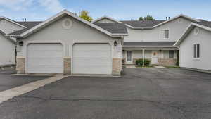 View of property featuring stucco siding, roof with shingles, and a garage