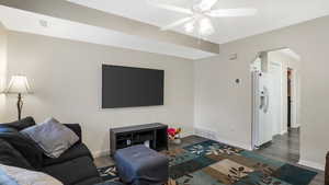Living room with arched walkways, ceiling fan, and wood finished floors