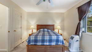 Bedroom with light carpet, a ceiling fan, and baseboards