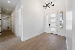 Foyer featuring a chandelier, light wood-type flooring, recessed lighting, and baseboards