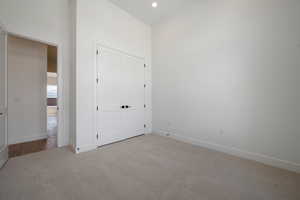 Unfurnished bedroom featuring light colored carpet, baseboards, recessed lighting, and a closet