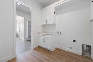Laundry room with electric dryer hookup, hookup for a washing machine, light wood-style flooring, and cabinet space