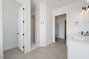 Bathroom featuring a marble finish shower, double vanity, and baseboards