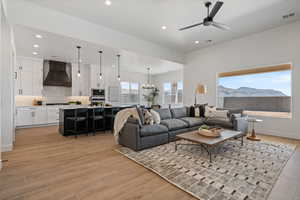 Living room with light wood finished floors, recessed lighting, ceiling fan, and a chandelier