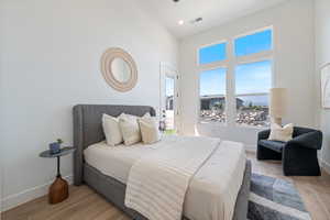 Bedroom with a towering ceiling, light wood finished floors, and recessed lighting