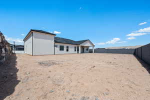 Rear view of house with a fenced backyard and stucco siding