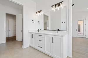 Bathroom with double vanity, baseboards, and tile patterned flooring