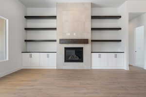 Unfurnished living room featuring light wood-style floors, baseboards, and a fireplace