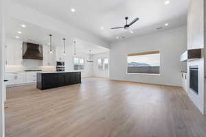 Kitchen with open floor plan, appliances with stainless steel finishes, custom range hood, a fireplace, and recessed lighting
