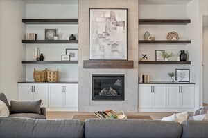 Living area featuring light wood-style floors, built in features, and a tile fireplace