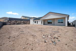 Rear view of house with stucco siding, a fenced backyard, and a patio area