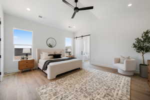 Bedroom with a barn door, lofted ceiling, recessed lighting, light wood-type flooring, and a ceiling fan