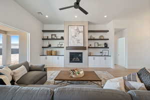 Living room with a ceiling fan, light wood finished floors, a tile fireplace, and recessed lighting