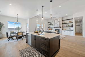 Kitchen with a chandelier, light countertops, dark brown cabinets, light wood-style floors, and recessed lighting