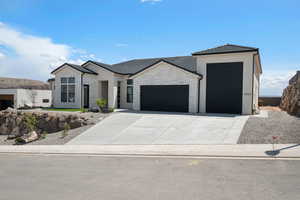 Contemporary home featuring an attached garage, concrete driveway, stone siding, and stucco siding