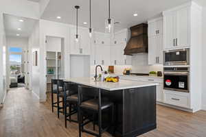 Kitchen featuring appliances with stainless steel finishes, light wood-style flooring, white cabinetry, light countertops, and recessed lighting