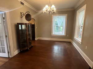 entry or possible dining area featuring dark wood-type flooring, arched walkways, a chandelier, ornamental molding, and baseboards