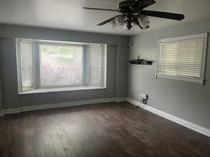 Empty room featuring a ceiling fan, wood finished floors, and baseboards