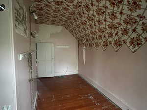 Hallway featuring lofted ceiling and hardwood / wood-style floors