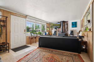 Entrance foyer featuring a wood stove, wooden walls, a textured ceiling, and light tile patterned floors