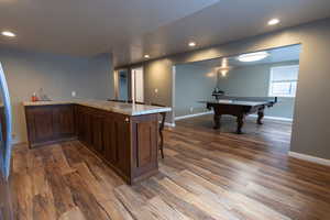 Kitchen featuring dark wood finished floors, recessed lighting, baseboards, pool table, and dark brown cabinets