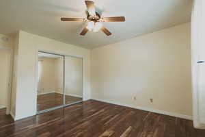 Unfurnished bedroom with wood finished floors, a closet, baseboards, and ceiling fan
