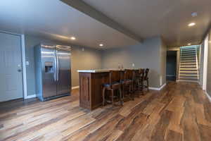 Kitchen featuring stainless steel fridge, wood finished floors, baseboards, a peninsula, and recessed lighting