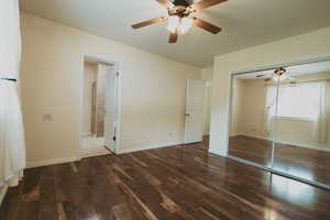 Unfurnished bedroom with wood finished floors, baseboards, a closet, a ceiling fan, and ensuite bathroom