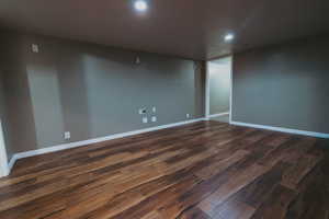 Unfurnished room with recessed lighting, dark wood-style flooring, and baseboards