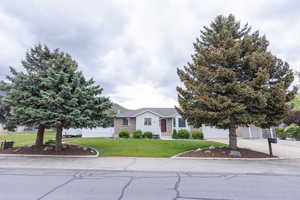 View of front of property featuring driveway, a front lawn, brick siding, and a garage