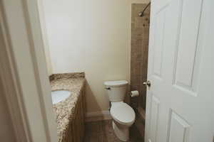 Full bathroom with vanity, toilet, tile patterned floors, a tile shower, and baseboards