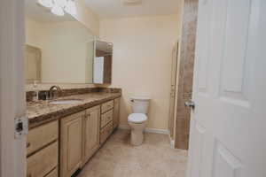 Full bath with toilet, vanity, tile patterned floors, and baseboards