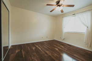 Unfurnished bedroom with dark wood-type flooring, baseboards, a closet, and ceiling fan