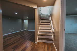 Staircase with wood finished floors, baseboards, and recessed lighting