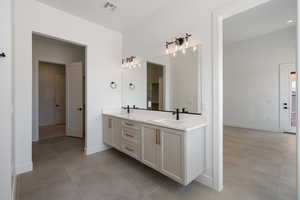 Full bath featuring double vanity, tile patterned floors, and baseboards