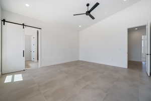Unfurnished room with a ceiling fan, a barn door, baseboards, high vaulted ceiling, and recessed lighting