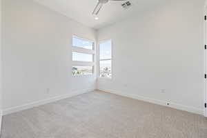 Spare room with light carpet, a ceiling fan, and baseboards