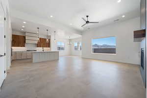 Unfurnished living room with recessed lighting, ceiling fan, baseboards, a chandelier, and a glass covered fireplace
