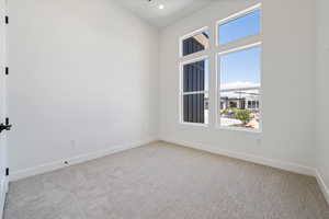 Spare room featuring healthy amount of natural light, carpet, baseboards, a towering ceiling, and recessed lighting