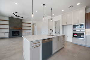 Kitchen featuring a sink, stainless steel appliances, a ceiling fan, light countertops, and a kitchen island with sink