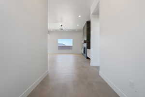 Hall featuring baseboards, concrete floors, and recessed lighting