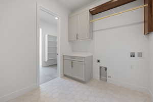 Clothes washing area with electric dryer hookup, hookup for a washing machine, cabinet space, and baseboards