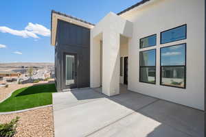 Entrance to property with a patio area, stucco siding, and board and batten siding