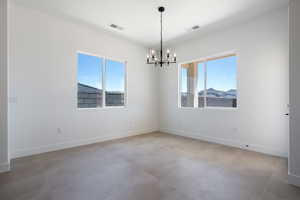 Unfurnished room with a chandelier, baseboards, and concrete floors